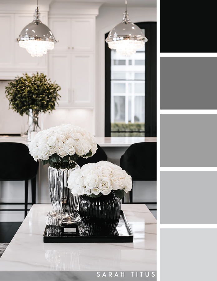 Sophisticated white kitchen with black stools, crystal pendant lights, white roses on a tray, and black framed doors in a soft gray, black, and silver color palette.