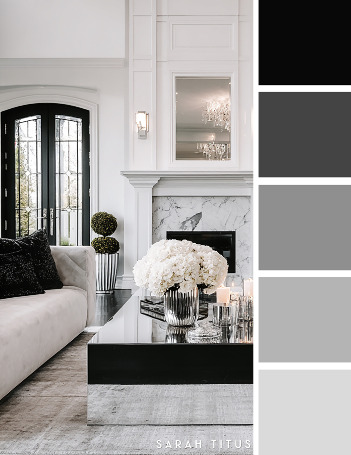 Luxe black and white living room with a marble fireplace, glossy black coffee table, white sofa, candles, silver decor, and soft white hydrangeas in a gray and silver palette.